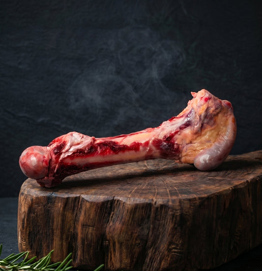 Raw meat bone on a wooden board with herbs and spices against a dark background