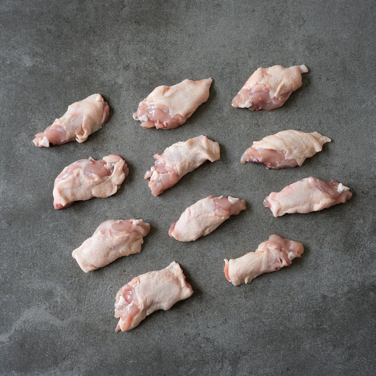 Raw chicken wings arranged on a gray surface