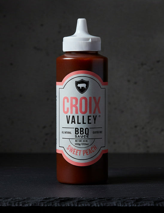 Bottle of Croix Valley Sweet Peach BBQ Sauce on a black background
