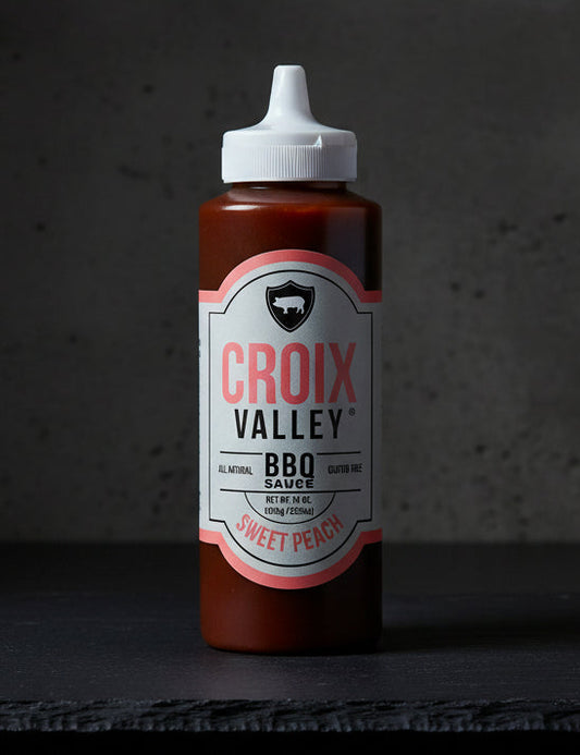 Bottle of Croix Valley Sweet Peach BBQ Sauce on a black background
