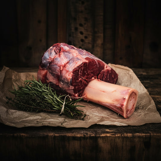 Raw meat with a bone and rosemary on a stone surface