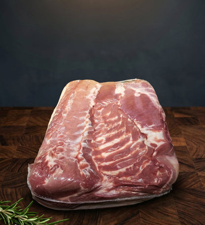 Raw pork belly on a wooden surface with a dark background