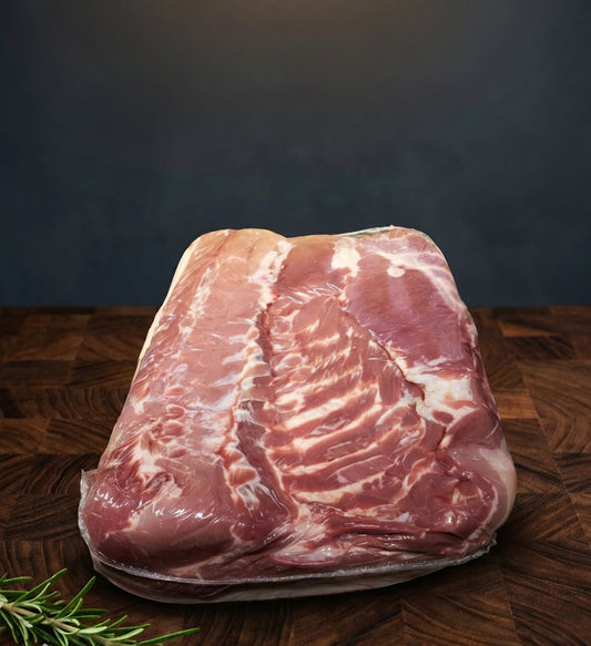 Raw pork belly on a wooden surface with a dark background